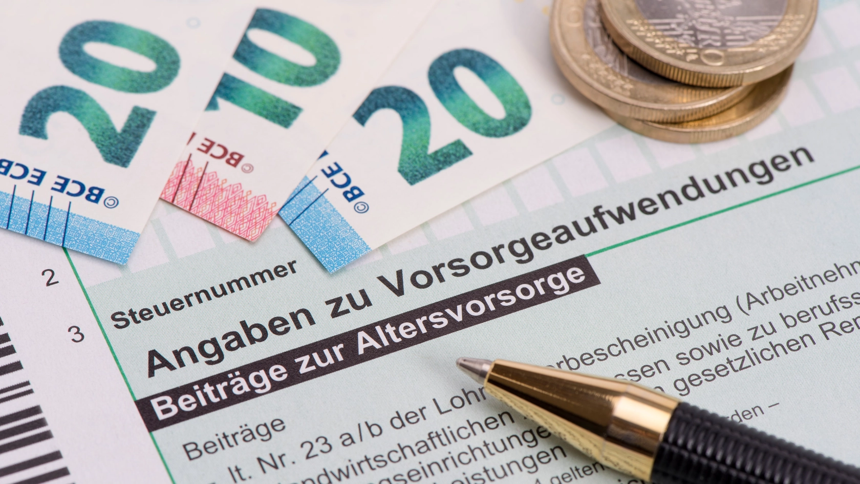 Geldscheine und Münzen liegen auf einem Formular zur Altervorsorge