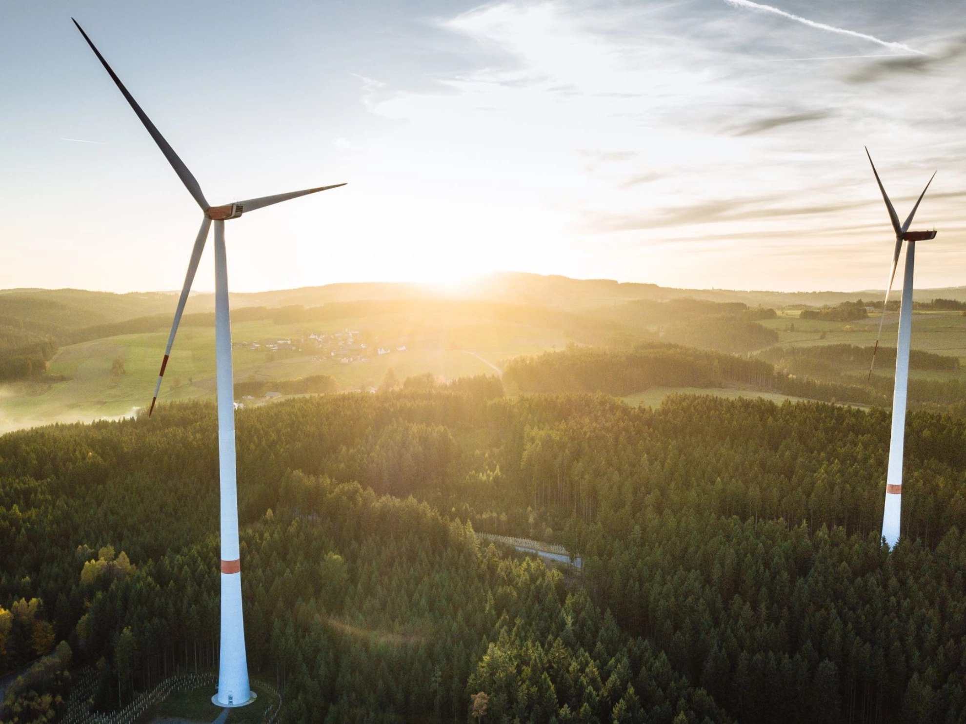 zwei Windkraftanlagen während eines Sonnenuntergangs